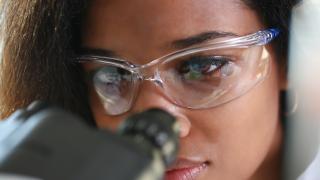 scientist looking thru microscope with goggles