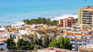 Overlooking beach in Andalusia, Spain with buildings and palm trees by the shore.